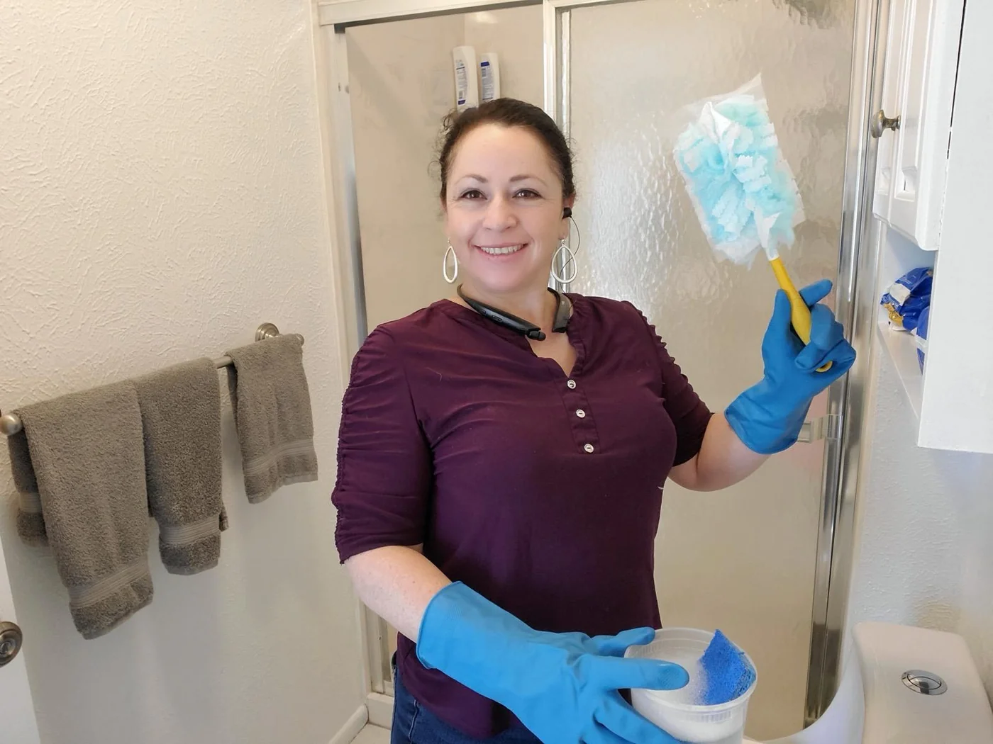 CleanVista team member in gloves cleaning a shower door in a Denver home